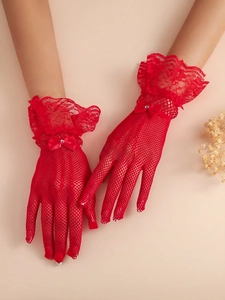 Close-up of red fishnet lace bridal gloves featuring a bow and rhinestone detail