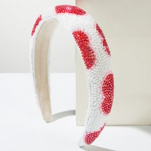 Close-up of handmade beaded headband with red heart patterns on white seed beads