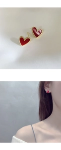 Detailed view of vintage gold-trimmed burgundy heart earrings on fabric and a model ear