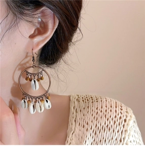 Detail of bohemian shell hoop earrings with vintage beads on a model for beach vacation style