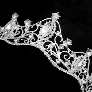Macro shot of silver bridal crown featuring intricate scroll patterns and sparkling crystals