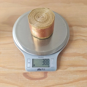Detail showing the 38.8g weight of a gold leaf ribbon with glitter on a digital scale