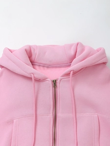 Detailed view of pink hooded sweatshirt neckline, metal zipper and soft knit fabric
