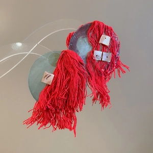 Detail view of bold red silk tassel earrings with gray discs and shell inlay details