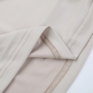 Détail macro de la robe en maille beige montrant la double couture et la texture de qualité