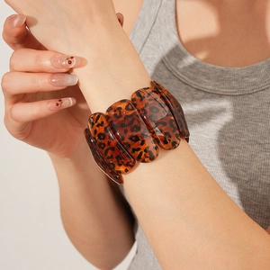 Gros plan d'un large bracelet en résine à motif léopard avec un design épissé unique