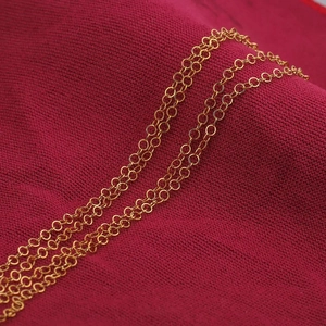 Golden stainless steel round link chain for DIY jewelry making on a red fabric background