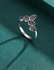 Detail view of clustered leaf ring with black pavé stones on textured green surface