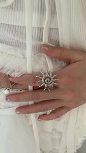 Detail of silver sunburst open ring with spiral texture on a soft lace background
