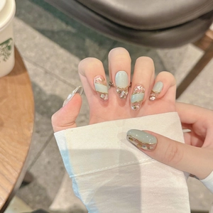 Handmade almond press-on nails in mint green with gold edges and seashell sequins