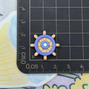Macro detail of a 2.5cm blue resin ship helm charm for DIY crafts and accessories