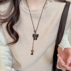 Sautoir avec pendentif nœud imprimé léopard porté sur un pull en maille blanc cassé