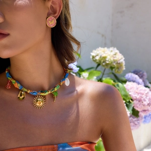 Detailed shot of pink butterfly earrings and sun charm necklace on a model