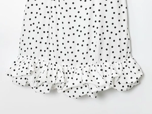 Gros plan détaillé d'une robe blanche à pois avec ourlet à volants multicouches