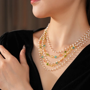 Detail of vintage multilayer pearl necklace with colorful glass gemstones on neck