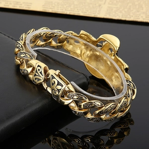 Macro detail of gold-plated vintage chain bracelet with black fleur-de-lis engravings