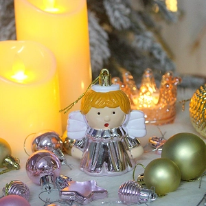 Close-up of a silver angel Christmas ornament with gold string on a festive background