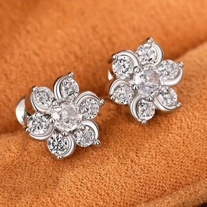 Sparkling zircon flower stud earrings in silver finish on a warm textured background