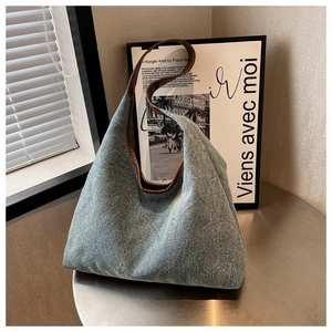 Detail of blue denim tote bag with quilted diamond pattern and brown leather handle