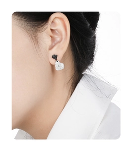 Detail of irregular black heart and silver textured stud earring worn by model