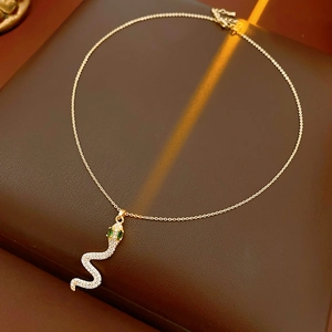 Dettaglio della collana d'oro con ciondolo a serpente in zircone e occhi di gemme verdi