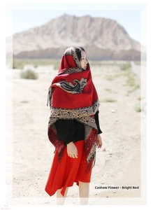 Macro detail of red cashmere shawl featuring ethnic paisley print and fringe at the desert