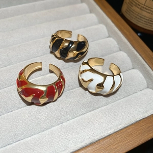 Close-up of three gold-plated chunky croissant rings with red, black, and white enamel inlay