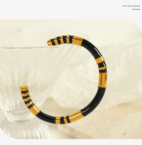 Detail showing high-gloss black enamel and gold-plated striped texture on a luxury bangle