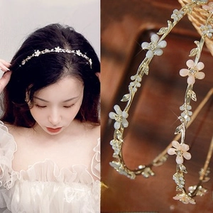 Detailed close-up showing gold wire leaf headband with white and pink flower blossoms