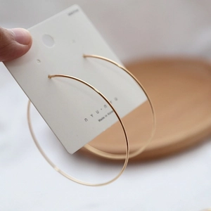 Minimalist large golden hoop earrings with 925 silver needle on a display card