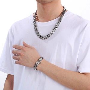 Detailed view of a silver 15mm Cuban link chain necklace and bracelet set on a model