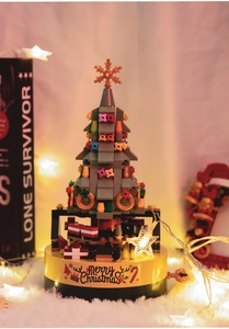 Close-up of building block Christmas tree music box on a soft white rug with warm lights