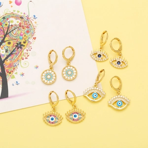Detailed flat lay of four pairs of golden evil eye earrings with colorful crystals