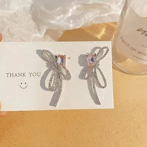 Detail of silver bow earrings with pink rectangular gemstone and micro-pave crystals