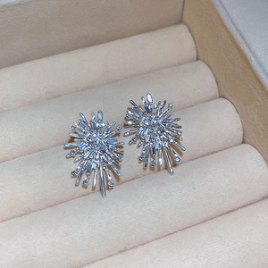 Close-up of silver stud earrings in firework design with zircons on beige jewelry box