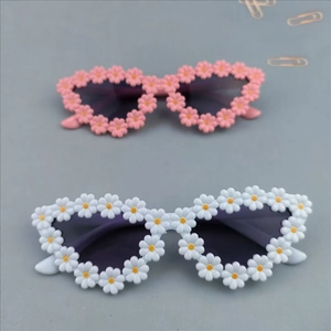 Close-up of white and pink daisy flower shaped sunglasses with dark lenses for kids