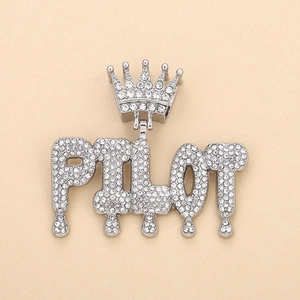 Close-up of silver-toned PILOT pendant with crown and teardrop detail in rhinestones