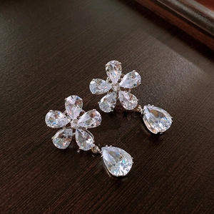 Detail of floral earrings with sparkling teardrop crystals on a dark wood background