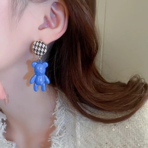 Close-up of blue bear drop earrings with houndstooth studs worn by a model