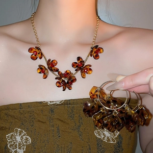 Detail of amber acrylic flower petals necklace and earrings set with red beads