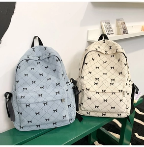 Detail of bow-knot ribbon backpacks in blue and beige with quilted pattern for students