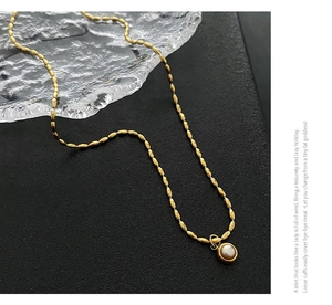 Detailed close-up of a gold titanium steel bead chain with a round pearl pendant