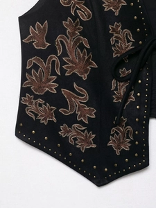 Close-up of bohemian suede vest featuring intricate floral embroidery and metallic rivets