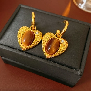 Close-up of vintage resin heart earrings with amber opal and crystals on a black box