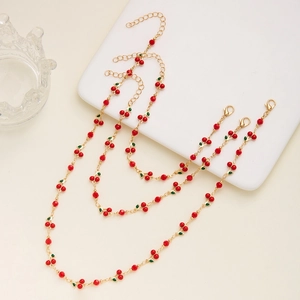 Detail of red cherry pendant jewelry set with beaded multi-layer necklace and bracelet