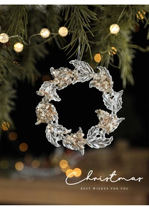 Close-up of clear acrylic Christmas wreath ornament with gold glitter on pine branch