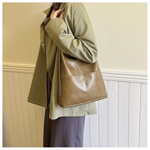 Sac seau en cuir PU marron porté par un mannequin montrant le design spacieux et le style rétro