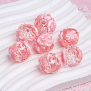 Detail shot of transparent pink DIY beads with white SUN pattern on a wavy tray