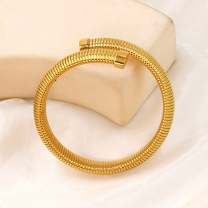 Detailed view of golden minimalist spiral bangle with textured metallic finish and sleek caps
