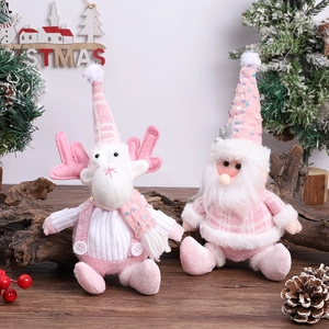 Pink sequin Santa and reindeer plush dolls sitting on a wood surface with festive decor